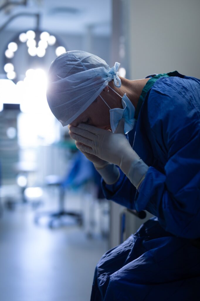 Upset female surgeon sitting on the operation bed in operation room